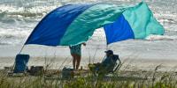 Photo shows a beachgoers sun canopy flapping in the strong winds at Tables Beach