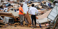 People stand among debris at Gene's Mobile Home Supply, a trailer park in Bogue Chitto, Miss., Thursday, May, 7, 2026, after a tornado cut across the state. 