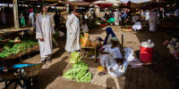 Customers buy vegetables at a market in Sudan.