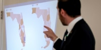 Oliver Larkin, Democratic candidate for Congress in Florida’s 23rd district, speaks during an emergency town hall that he held to address Florida Republicans’ newly approved congressional redistricting map (seen on wall).