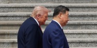 Donald Trump and Xi Jinping walk side-by-side in front of a concrete staircase.