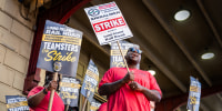 Olivier Desinor leads striking workers in chants during a picket outside