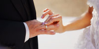 The bride puts the wedding ring on the groom's finger.