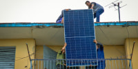Solar panel specialists lift a panel onto the rooftop of a multi-family building in Matanzas, Cuba, on April 13, 2026.