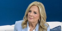 Jill Biden seated on a white couch in front of a blue wall