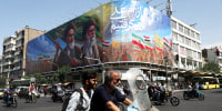 People ride past a billboard depicting the late leader of the Islamic Revolution, Ayatollah Ruhollah Khomeini, and the late Iran's Supreme Leader Ayatollah Ali Khamenei, on a street in Tehran