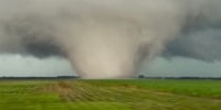 A large tornado moves over field in Illinois' Livingston County, as local media reported severe weather in Chicago area leaving major damage in its wake.