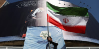 A man holds an Iranian flag on a street, in Tehran, Iran