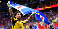 Vozinha raises the Cape Verde flag while standing on the soccer field
