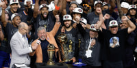 New York Knicks players celebrate while standing with their coach during an after-game press conference.