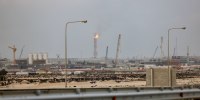An industrial landscape photographed from behind a roadway barricade.
