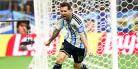 Lionel Messi runs in celebration near a soccer net on the field