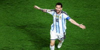 Lionel Messi runs on the soccer field with his arms outstretched in celebration