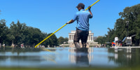 A U.S. National Park Service employee uses a vacuum pump to clean algae off the bottom of the newly repainted Lincoln Memorial Reflecting Pool on the National Mall