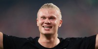 Erling Haaland smiles while standing on the football field