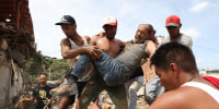 Neighbors carry a man rescued from the rubble of a collapsed building the day after earthquakes struck La Guaira, Venezuela, Thursday, June 25, 2026. 