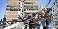 People work together to move a concrete slab with rebar sticking out of it.