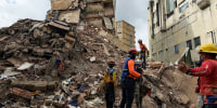 Workers search for people amongst the rubble of an apartment building