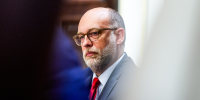 Russell Vought is seen between two blurred figures