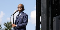 Al Sharpton standing at a microphone outdoors.