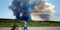 Local residents walk past the smoke of a fire at the Russian e-commerce firm Wildberries' logistics complexes.