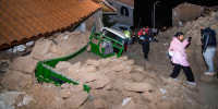 People walk amid debris outside near houses, photo taken with flash at night