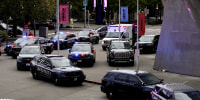 A dozen law enforcement vehicles with lights flashing parked outside an event center in downtown Seattle.