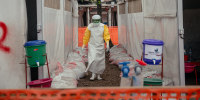 A Doctors Without Borders (MSF) doctor wearing personal protective equipment moves through the isolated red zone to monitor patients.