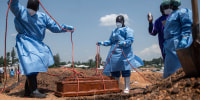 Teams from the International Federation of the Red Cross and Red Crescent Societies prepare for burial at Mbiyo cemetery.