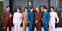 From left, V, Suga, Jin, Jungkook, RM, Jimin and J-Hope stand on the red carpet in different colored suits