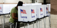A person stands at a voting booth