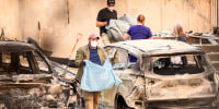 Residents carry the remains of deceased dogs at a home burned in the Old Trails fire in Spokane, Wash., on Aug. 4, 2026.