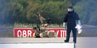 A forensic technician works alongside a bomb-disposal robot.