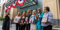 Parents hold pictures of their children.