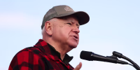 Tim Walz speaks, wearing a red plaid button up