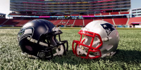 Two football helmets lie on the turf facing each other. 