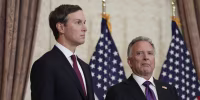 Jared Kushner and Steve Witkoff stand in front of two American flags.