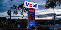 A sign displays fuel prices at a Mobil gas station