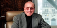 Clive Davis sits at a desk in an office by a window