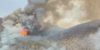 Close-up aerial video showing large billowing flames and massive plumes of smoke surrounding mountains in Eureka, Utah, on June 24, 2026.