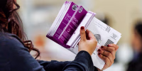 Vote by Mail ballots are inspected by a worker who flips through the envelope