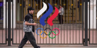 A man walks past a fence with Olympic Rings in front of the Russian National Olympic Committee building in Moscow.