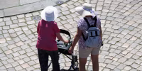 Women walking on a stone street Dresden's Old Town wearing sun hats. One woman has a walker.