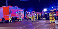 Emergency workers in fluorescent safety gear in front of ambulances at night.