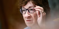 Susan Collins adjusts her glasses while seated