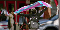A person holds a transgender flag in the air. 