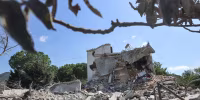 A destroyed building surrounded by rubble outside