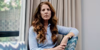 Lisa Parker looks directly toward the camera while seated at a dining table at home.