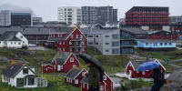 People with umbrellas walk in the rain in Nuuk.