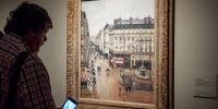 Museum goer looks at the painting 'Rue Saint-Honore por la tarde. Efecto de lluvia.'